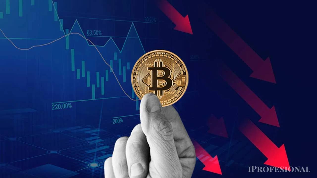 Mano sosteniendo bitcoin frente a gráficos financieros descendentes y flechas rojas
